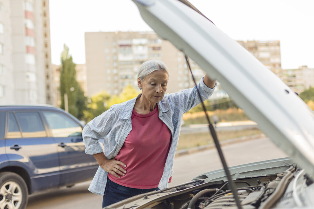 Senior woman looking at car engine